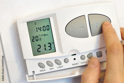 Photo: hand pressing button on digital thermostat hand pressing button on digital thermostat