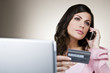 A young woman on the phone, holding her credit card