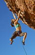 Female climber clinging to a cliff.