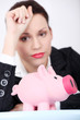 Depressed businesswoman looking at her piggy bank. Depressed businesswoman looking at her piggy bank.