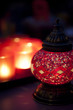Red Arabian style candle holder with chandeliers in the backgrou