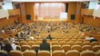 Several people sit on chair in hall and watch event