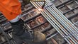 Worker legs in orange clothes weld metal grating