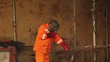 Worker in orange clothes weld metal gratings by acetylene torch