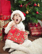 Child with gift in front of christmas tree