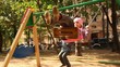 Boy and girl sway on swing, then children stoped and go away