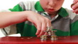 boy makes highly complicated figure with coins on red base