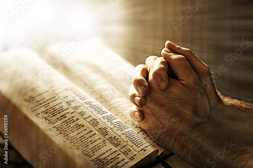 Photo: Man praying over a Bible Man praying over a Bible