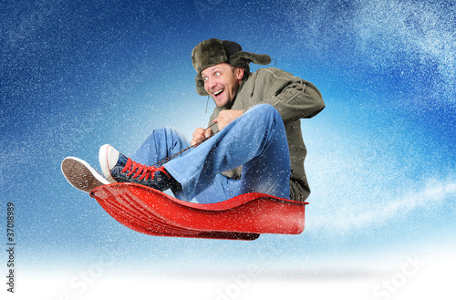 Photo: Cool young man fly on a sled in the snow Cool young man fly on a sled in the snow