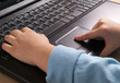 Children's hands on the keyboard, black notebook