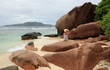 femme sur plage de sable blanc et rochers aux seychelles