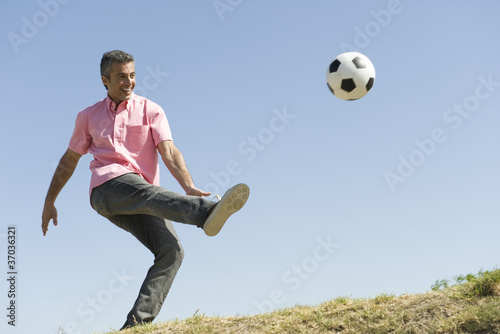 Photo: Man playing with soccer ball outdoors, smiling Man playing with soccer ball outdoors, smiling