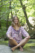 Young woman sitting in lotus position on rock