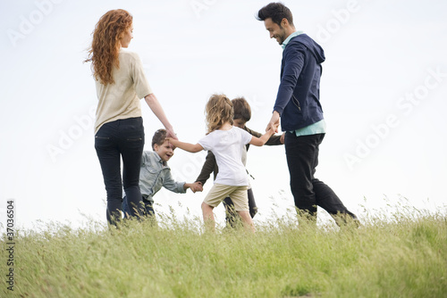 Foto: Family playing ring-around-the-rosy in meadow Family playing ring-around-the-rosy in meadow