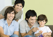 Three young men and little boy playing video games