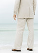 Businessman standing on beach, low section, rear view