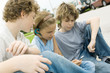 Children sitting in street, one with mp3 player