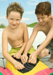 Two boys untangling kite string on beach
