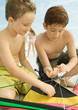Boys preparing kite on beach
