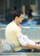 Teenage couple sitting outdoors, girl leaning against boy