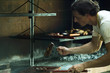 Photo: Man grilling meat on barbecue, putting meat onto wooden board Man grilling meat on barbecue, putting meat onto wooden board