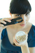 Woman looking at yogurt through magnifying glass
