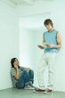 Teenage boy using cell phone while friend looks at book