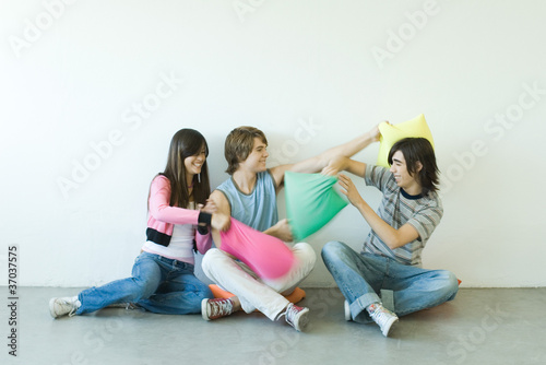 Photo: Group of young friends having pillow fight Group of young friends having pillow fight