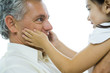 Man holding up little girl, girl's hands on man's cheeks, close-up
