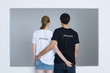 Photo: Young couple wearing customized tee-shirts, arms around each other's waists, rear view Young couple wearing customized tee-shirts, arms around each other's waists, rear view