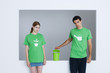 Photo: Young adults wearing tee-shirts printed with watering can and potted plant, man opening small garbage can Young adults wearing tee-shirts printed with watering can and potted plant, man opening small garbage can