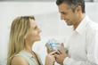 Couple exchanging gift, smiling at each other, side view