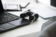 Binoculars on desk with laptop computer and notebook