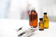Medical tray with forceps, syringe, medicine bottles in background