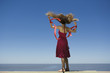 Young woman at beach looking at view, holding streamers in breeze