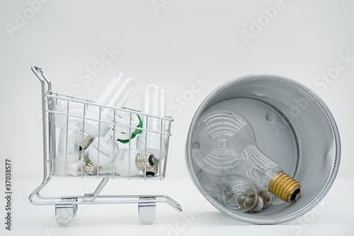 Photo: Shopping cart containing energy efficient light bulbs next to garbage can containing conventional light bulbs Shopping cart containing energy efficient light bulbs next to garbage can containing conventional light bulbs