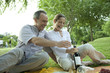 Mature couple having picnic outdoors, opening bottle of wine