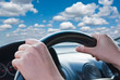 Driver's hands on a steering wheel of a car
