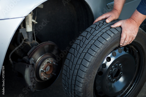Photo: mechanic changing a wheel of a modern car mechanic changing a wheel of a modern car