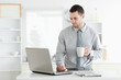 Foto: Businessman using a laptop while drinking coffee Businessman using a laptop while drinking coffee