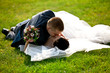 Newly married couple lying and kissing on grass Newly married couple lying and kissing on grass