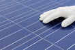 Hand mit weissem Handschuh vor Solarzellen