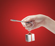Hand holding key with a keychain in the shape of the gift box