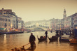 Rialto Bridge and gondolas at a foggy autumn evening in Venice.