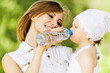 Photo: young charming caring mother gives daughter drink young charming caring mother gives daughter drink
