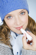 A young woman applying lip balm, in wintertime