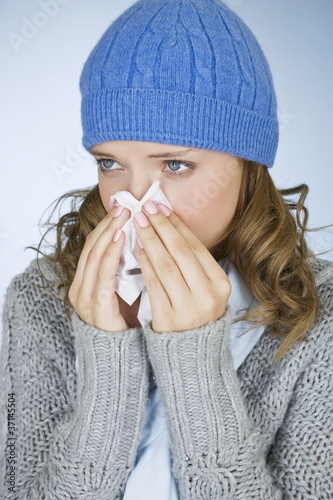 Photo: A young woman blowing her nose A young woman blowing her nose