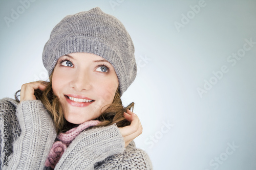 Photo: Portrait of a young woman wearing a grey woollen hat, smiling Portrait of a young woman wearing a grey woollen hat, smiling
