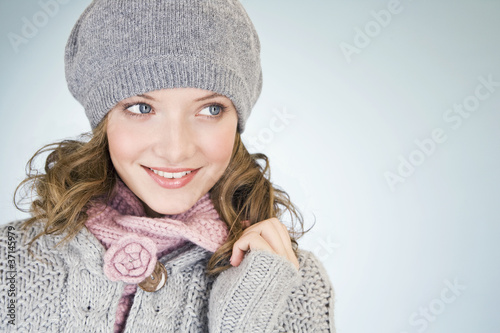 Photo: Portrait of a young woman wearing a grey woollen hat, smiling Portrait of a young woman wearing a grey woollen hat, smiling