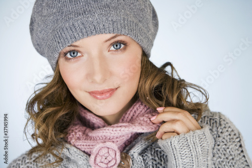 Photo: Portrait of a young woman wearing a grey woollen hat, smiling Portrait of a young woman wearing a grey woollen hat, smiling